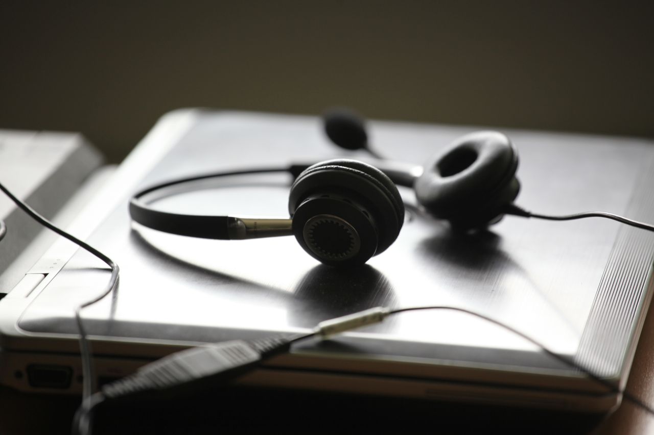 Black headphones lying on a closed silver laptop, symbolizing remote work or digital communication.